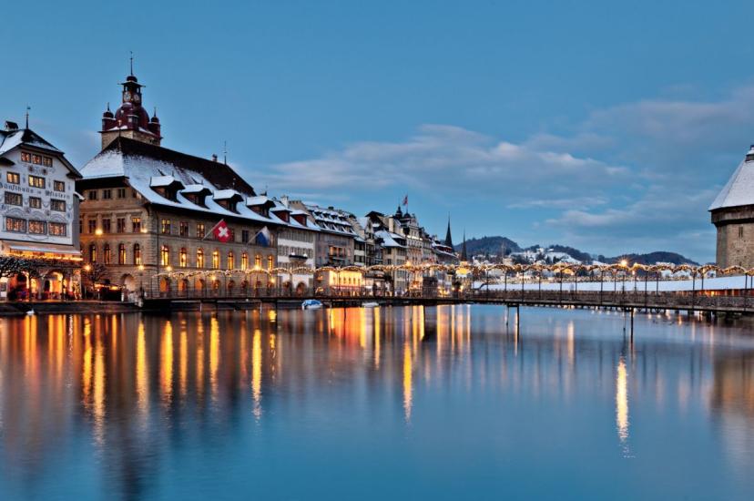 View of Lucerne at dusk with buildings lit up and snow on rooftops