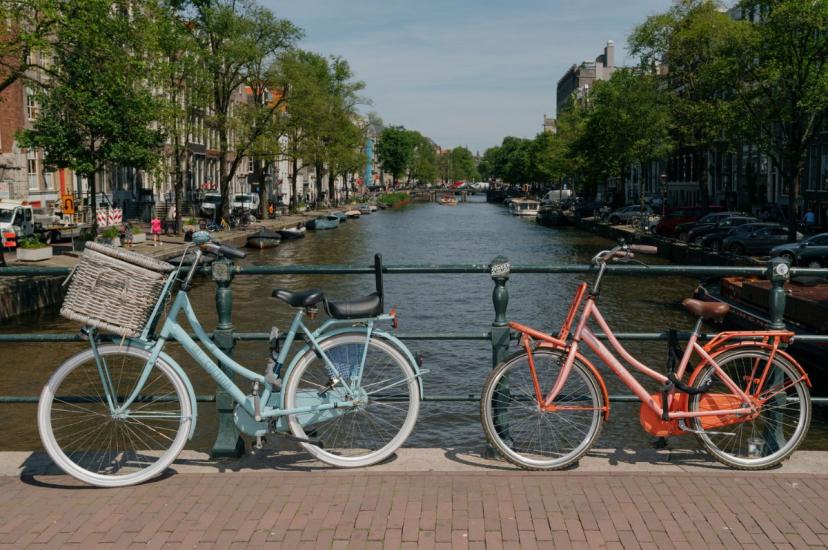 Bikes rest on hand rail with canal view in background in Amsterdam
