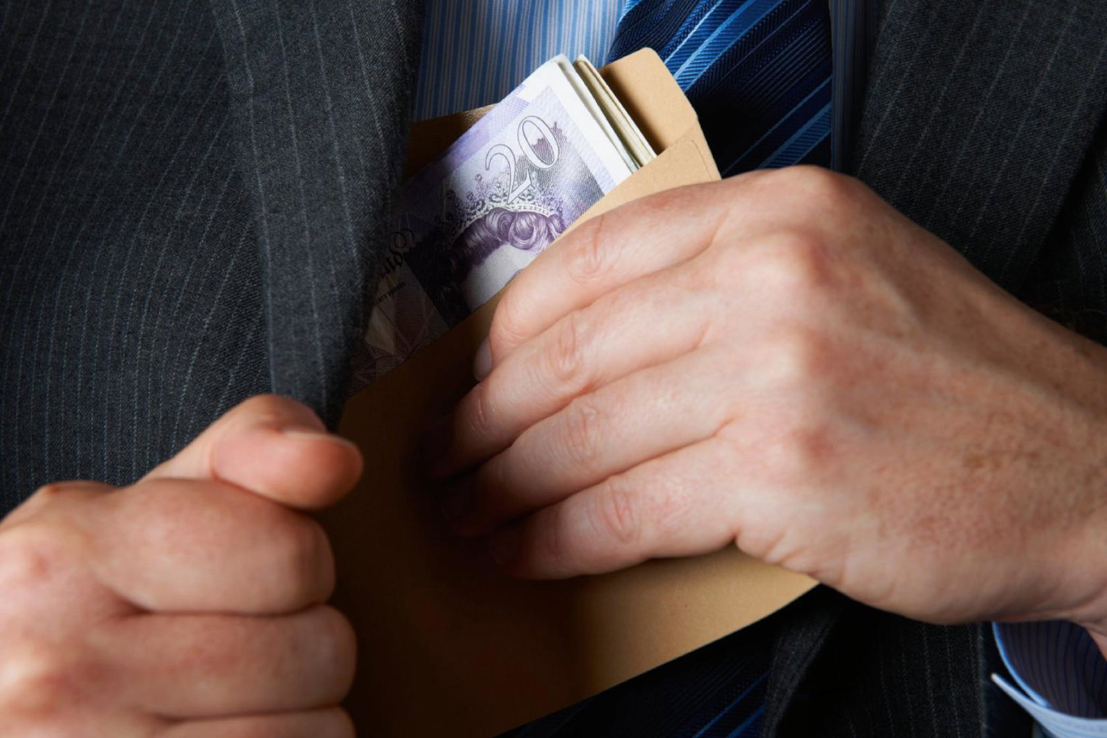 A man places a roll of bank notes in his jacket pocket