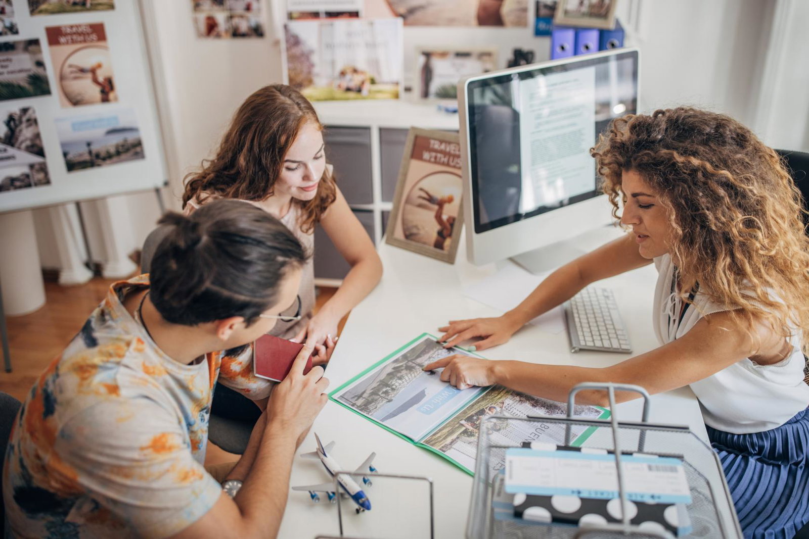 A travel agent helps a young couple with an enquiry