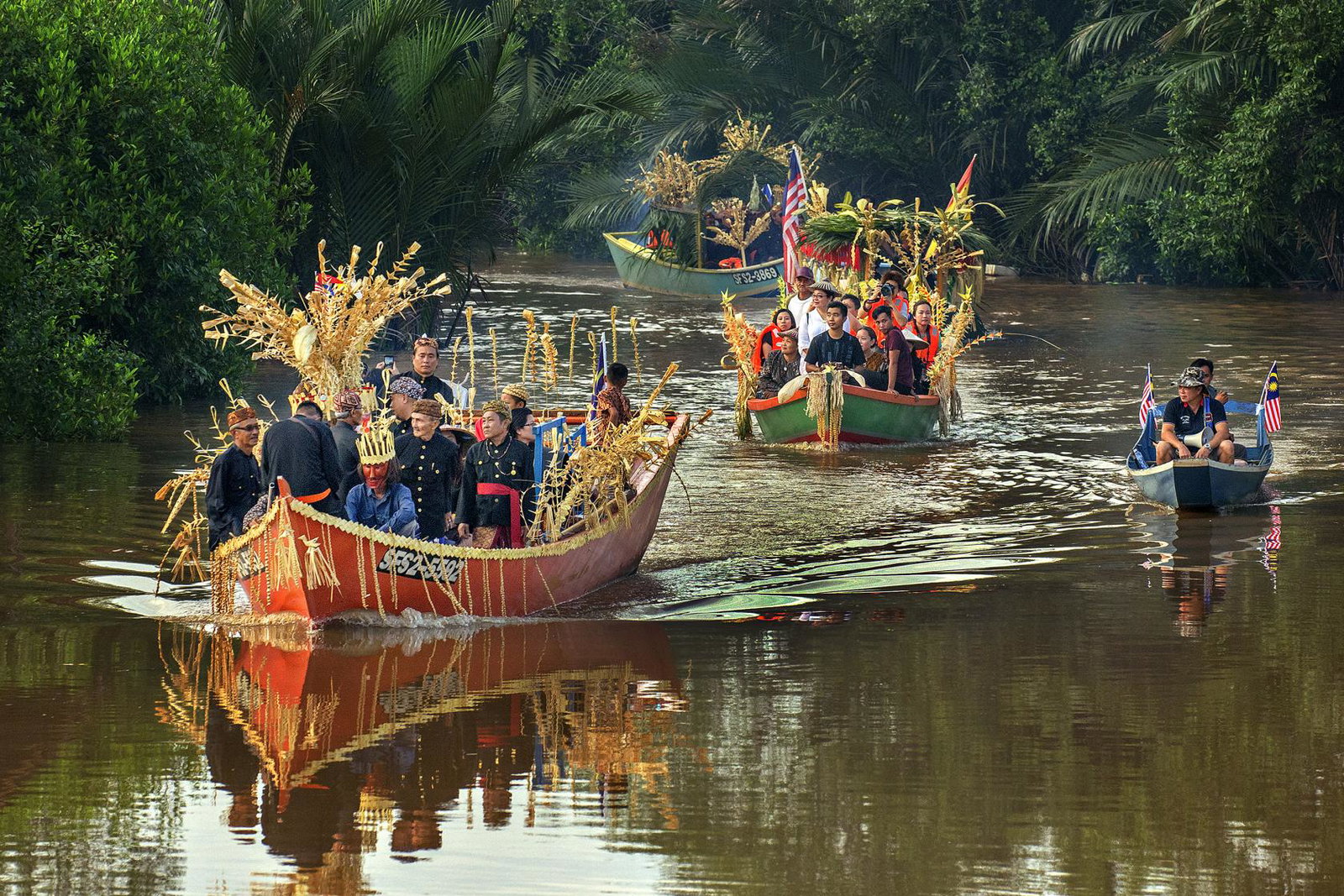 Sarawak locals in two boats moving down a brown river for a festival