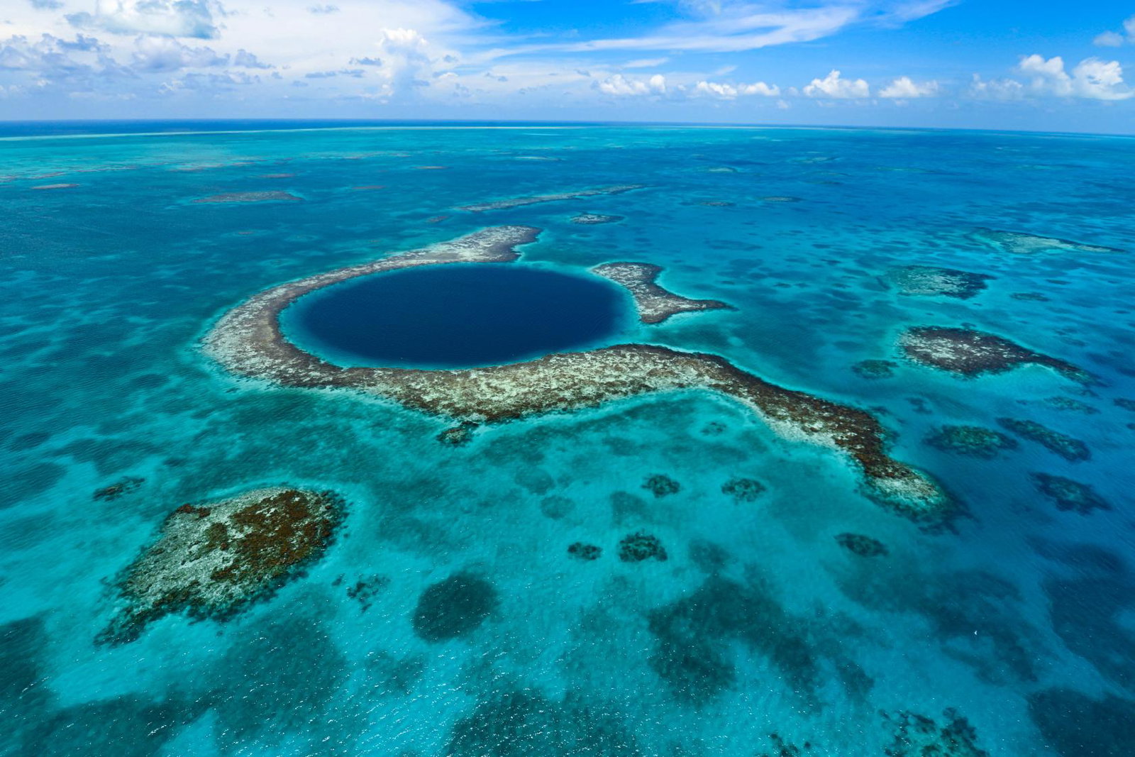 View of Belize Blue Hole from above, a dark blue circle in the middle of clear ocean