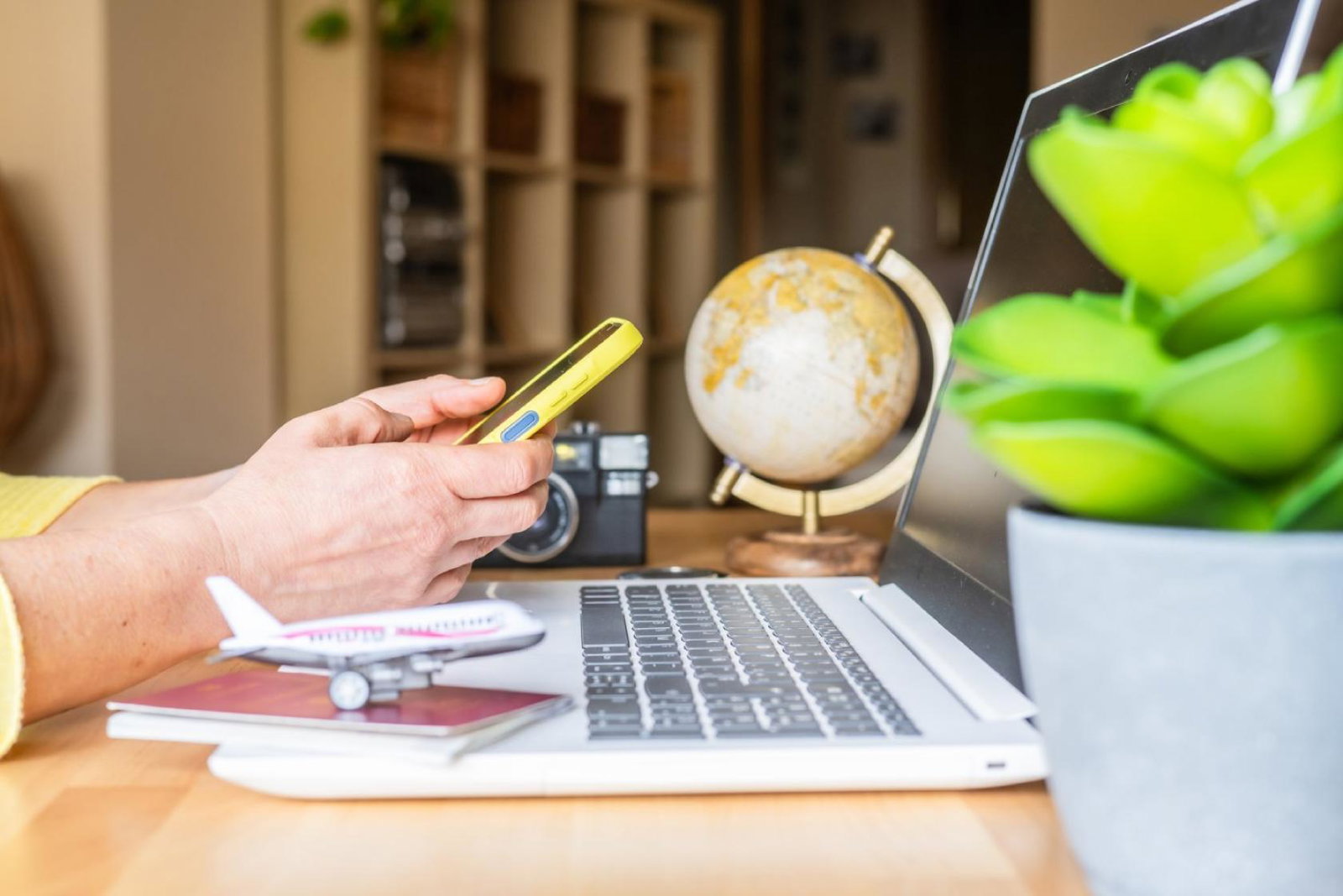 Person using a phone sitting at a laptop