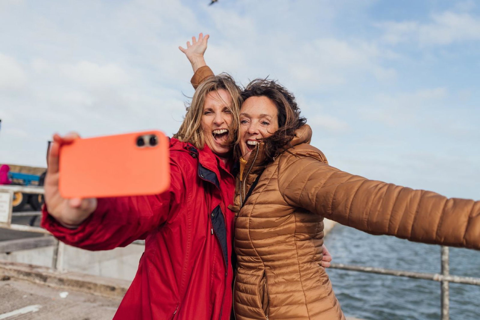 Two women take a selfie with the sea in the background