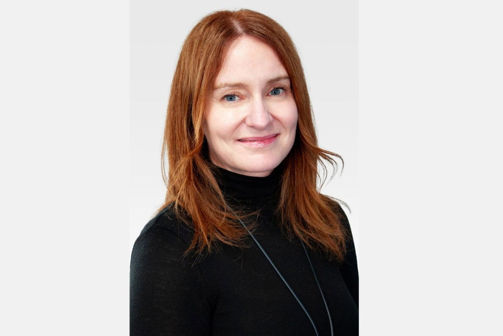 Smiling woman with red long hair and black turtleneck 