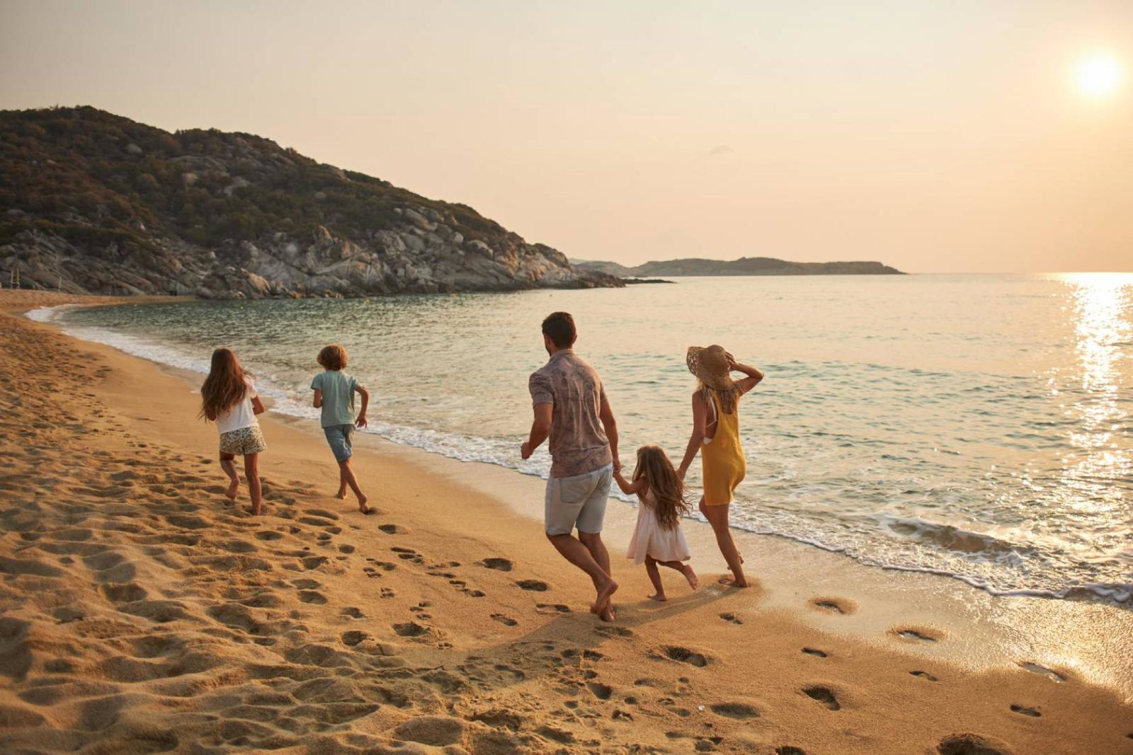 A family of five frolic happily on a sunny beach