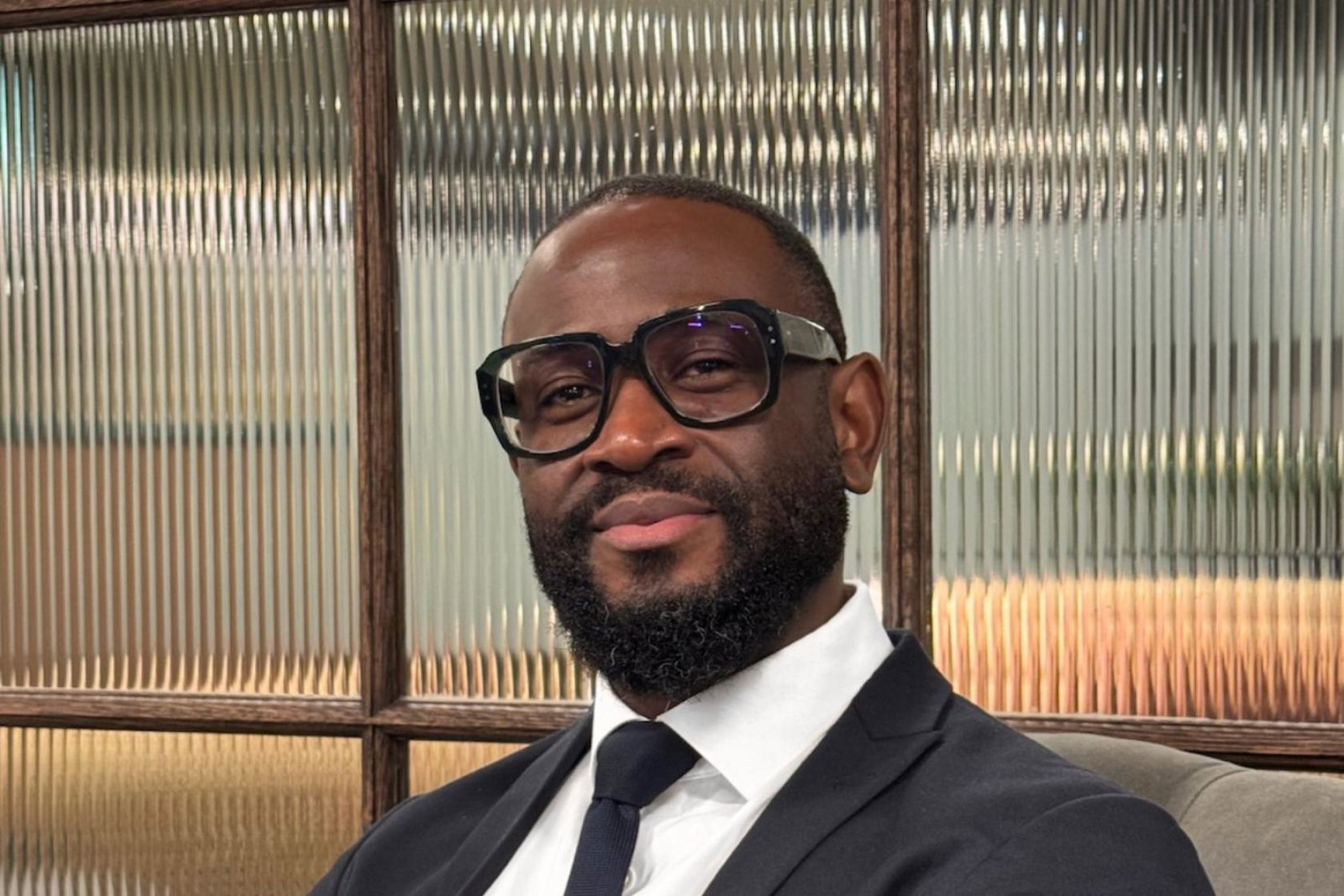 Man smiling, wearing glasses and suit 