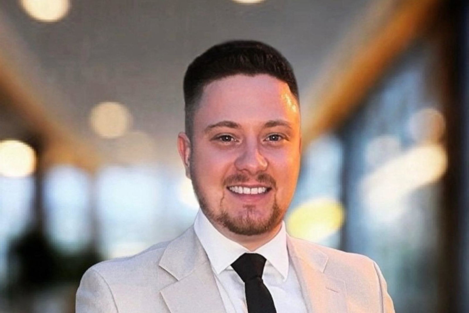 Man with brown hair and beard smiling at camera 