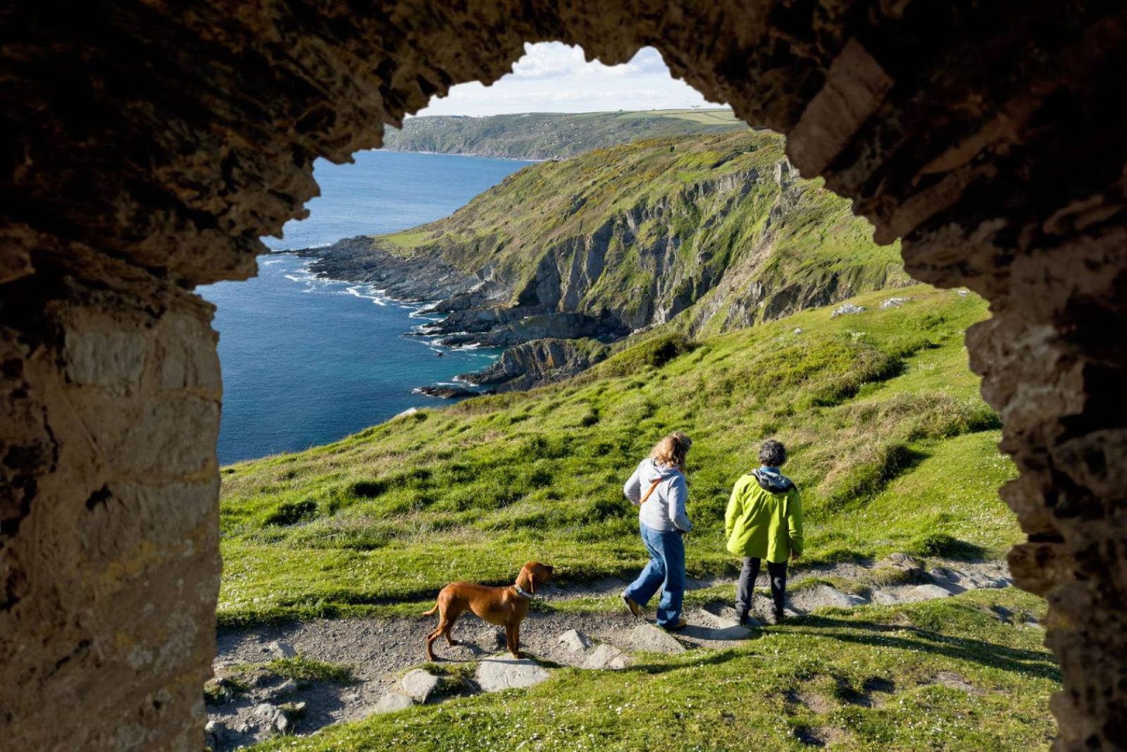 Couple with dog walking in the British coastal countryside