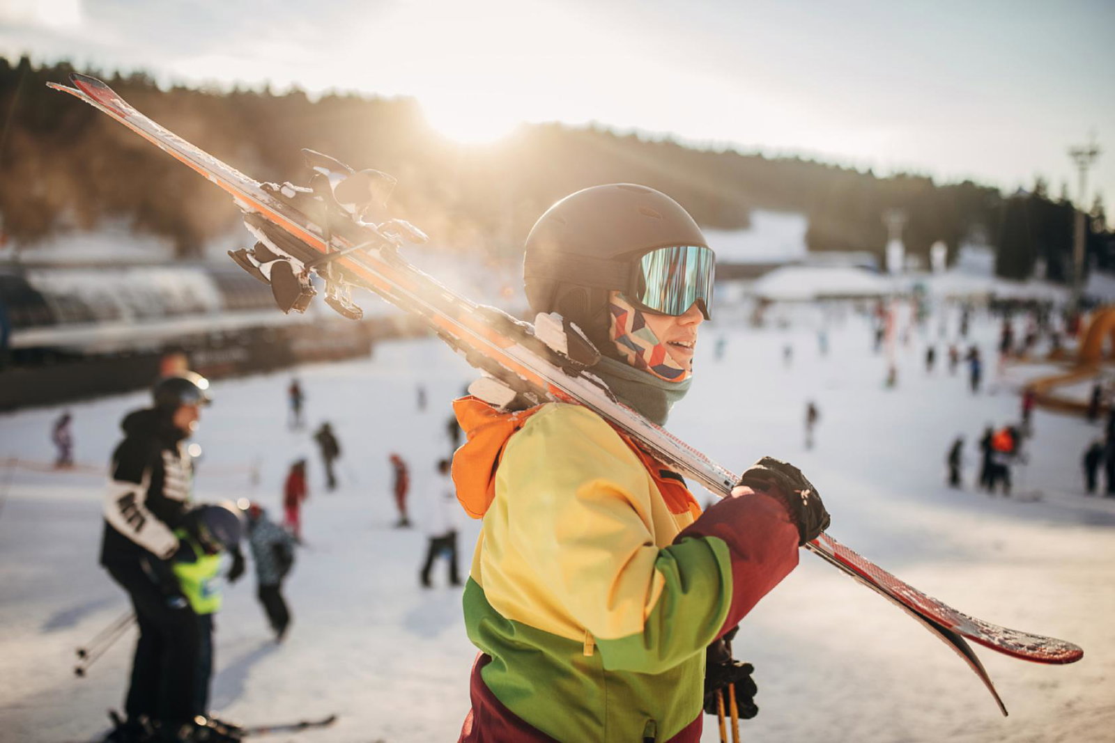 A skier with their skies over their shoulder