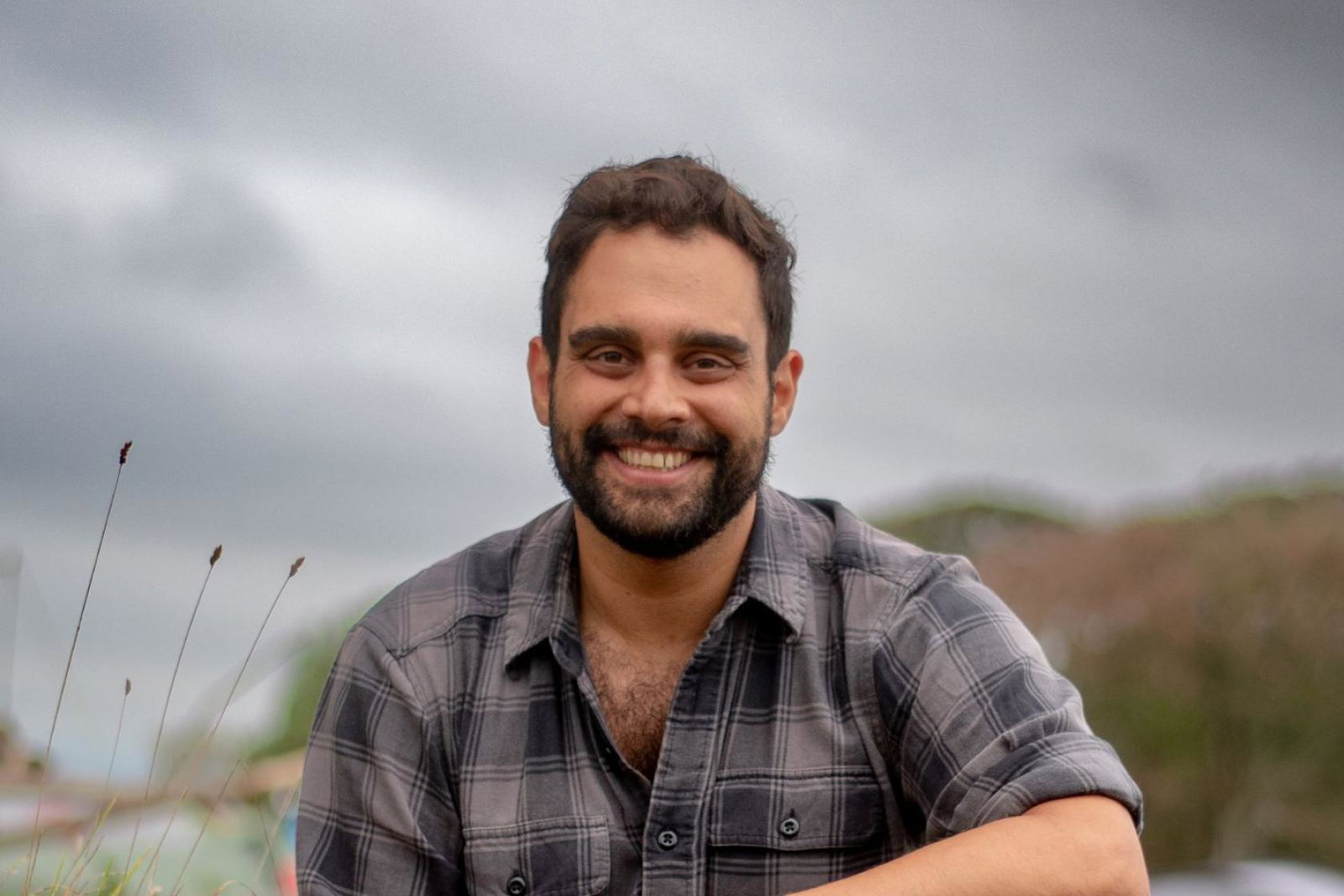 Man smiling in tartan shirt with mountain background 