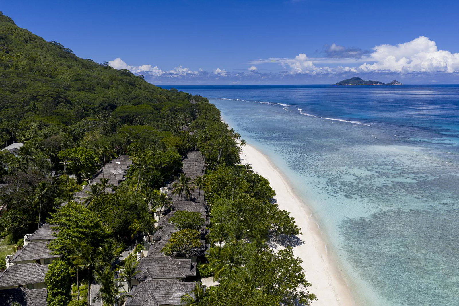 Villas line along a white-sand shoreline with blue oceans and backed by rainforests