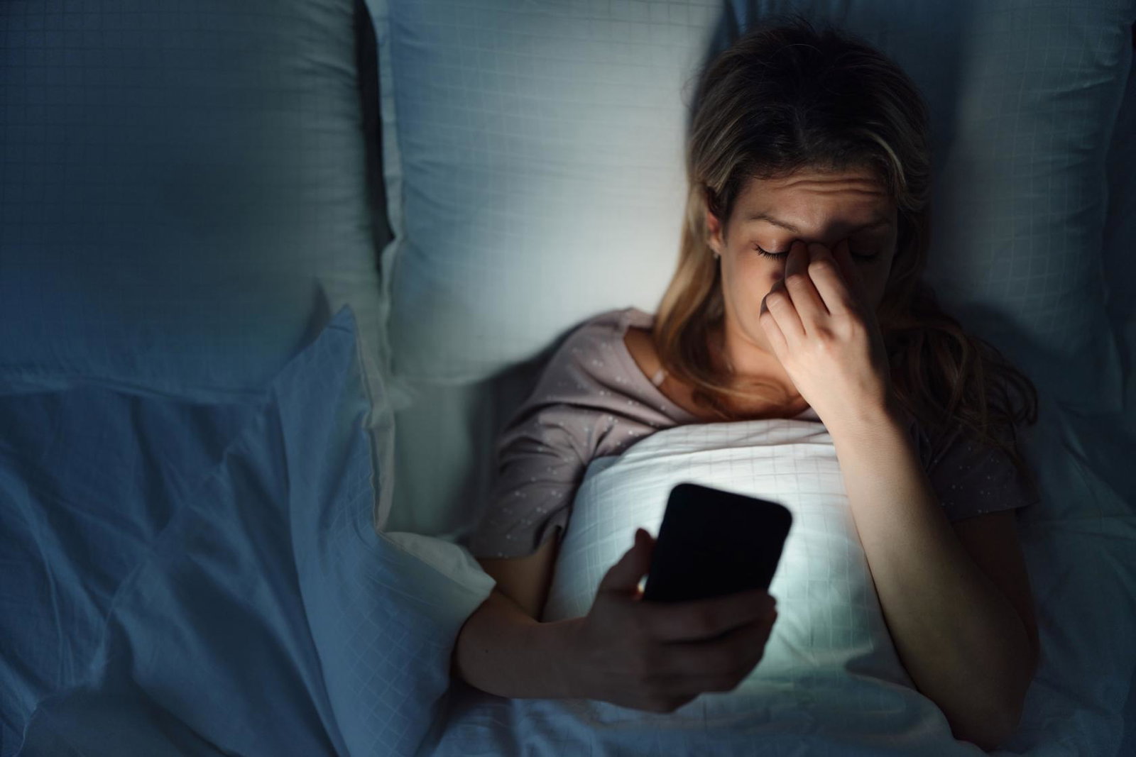 Woman in bed looking at phone