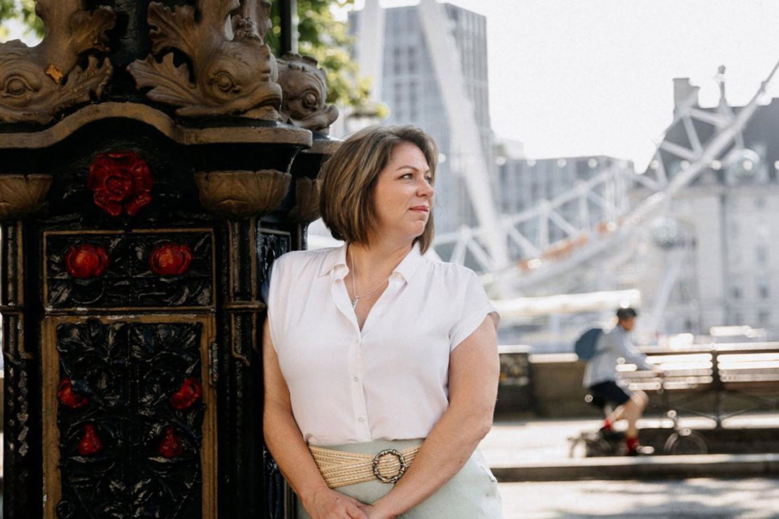 Brown haired woman outdoors in London, wearing white top and looking to the side