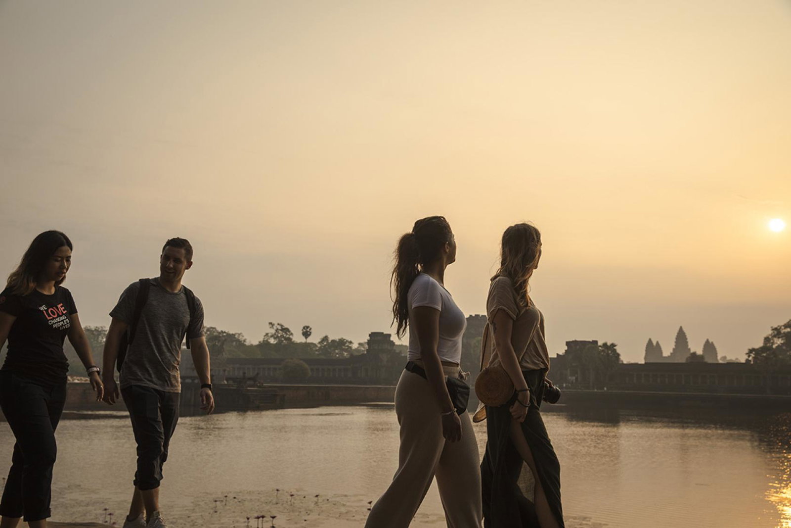 Group walking past Cambodia's Angkor Wat temple at sunrise