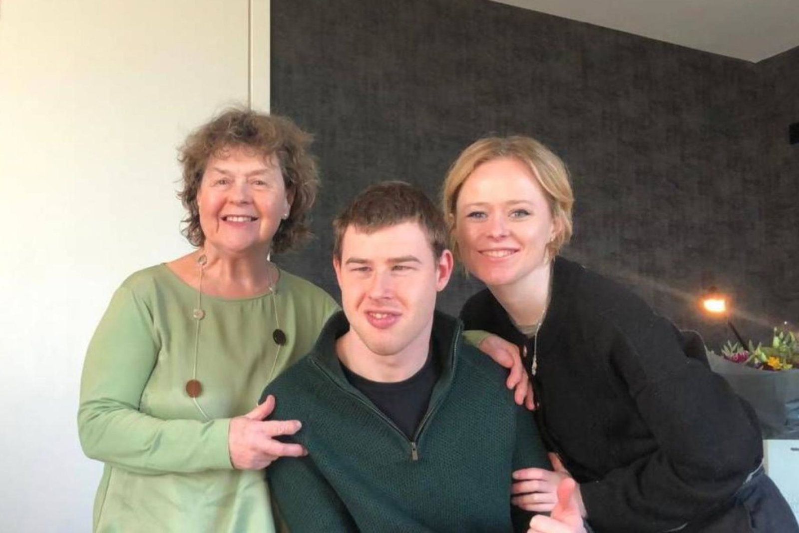 A family photo of a smiling older mother, adult son and daughter 