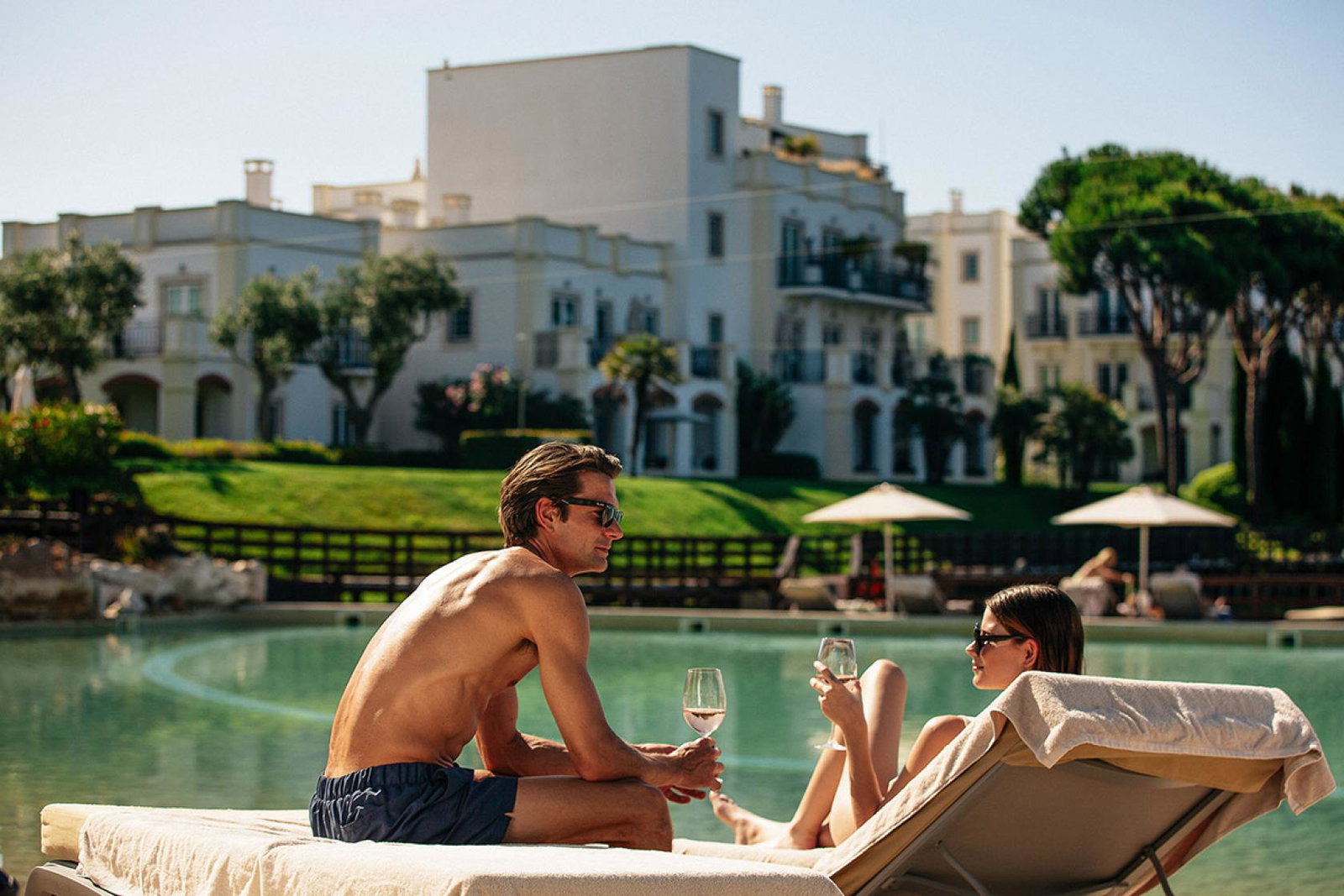 Man and woman sitting on sunchairs beside hotel pool
