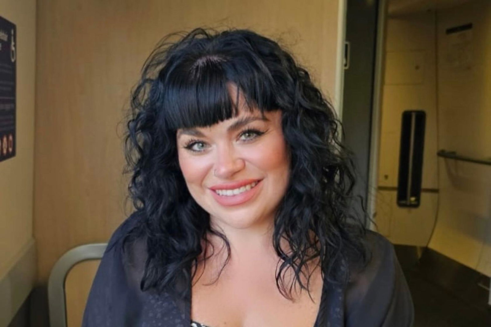 White woman with black curly hair smiling 