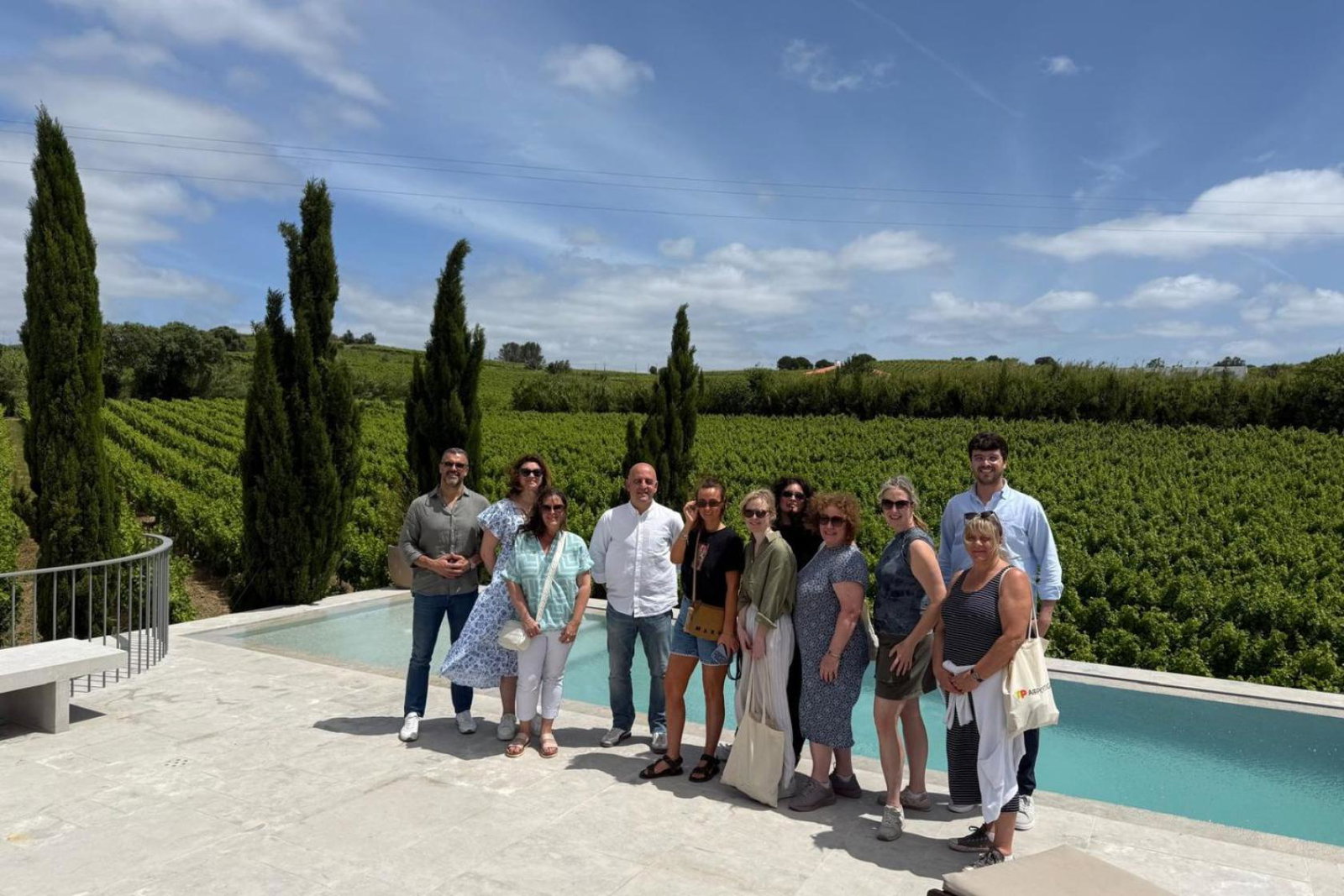 Group of travel agents standing and smiling by a private outdoor pool in rural Portugal 