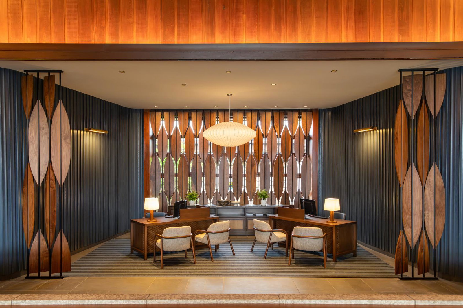 The redesigned lobby reception area at Fairmont Jasper Park Lodge, featuring warm wood panelling, mid-century modern furnishings and a statement pendant light, following the 2026 renovation.
