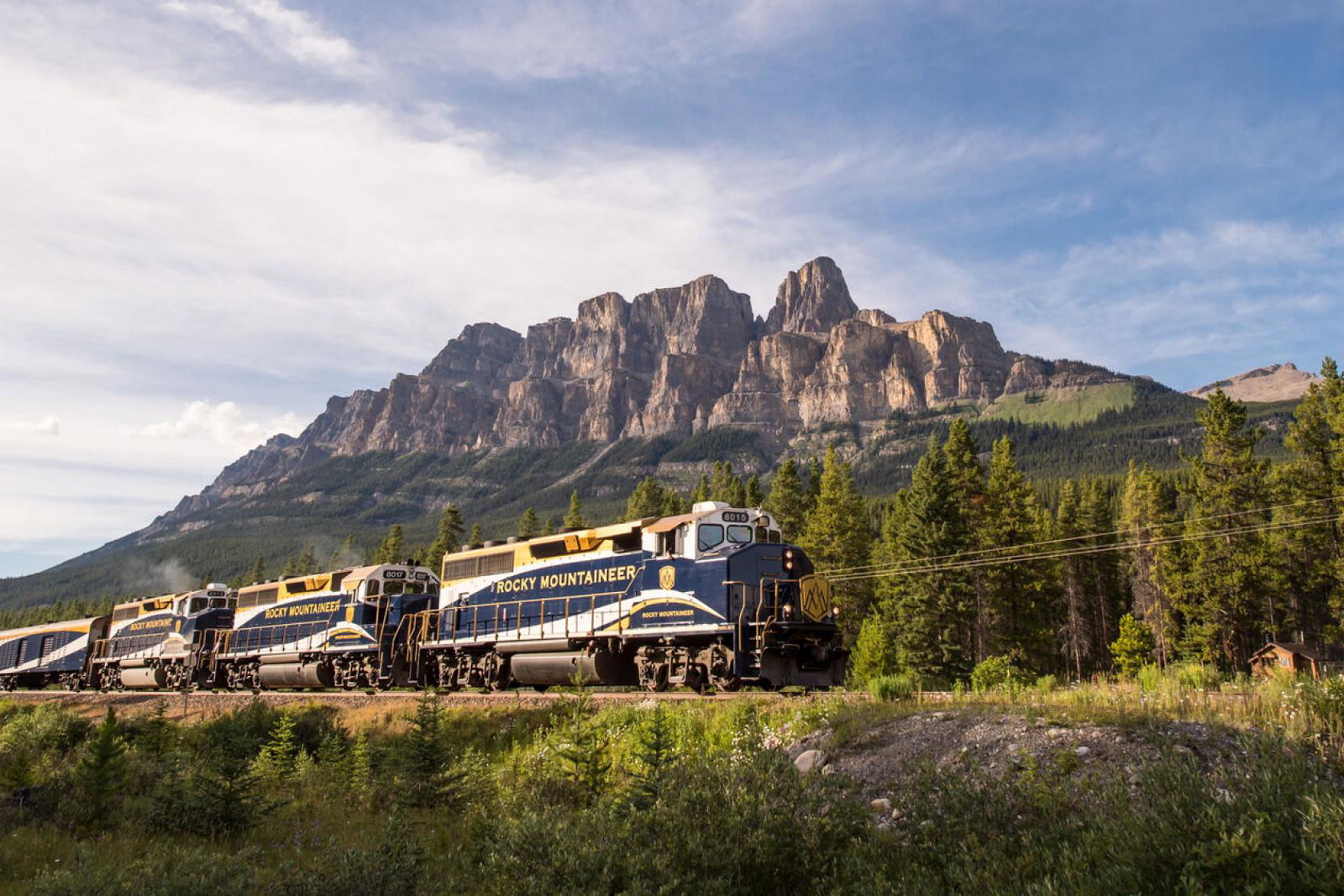 An image of Canada's Rocky Mountaineer train as it passes by the Rocky Mountains at dusk