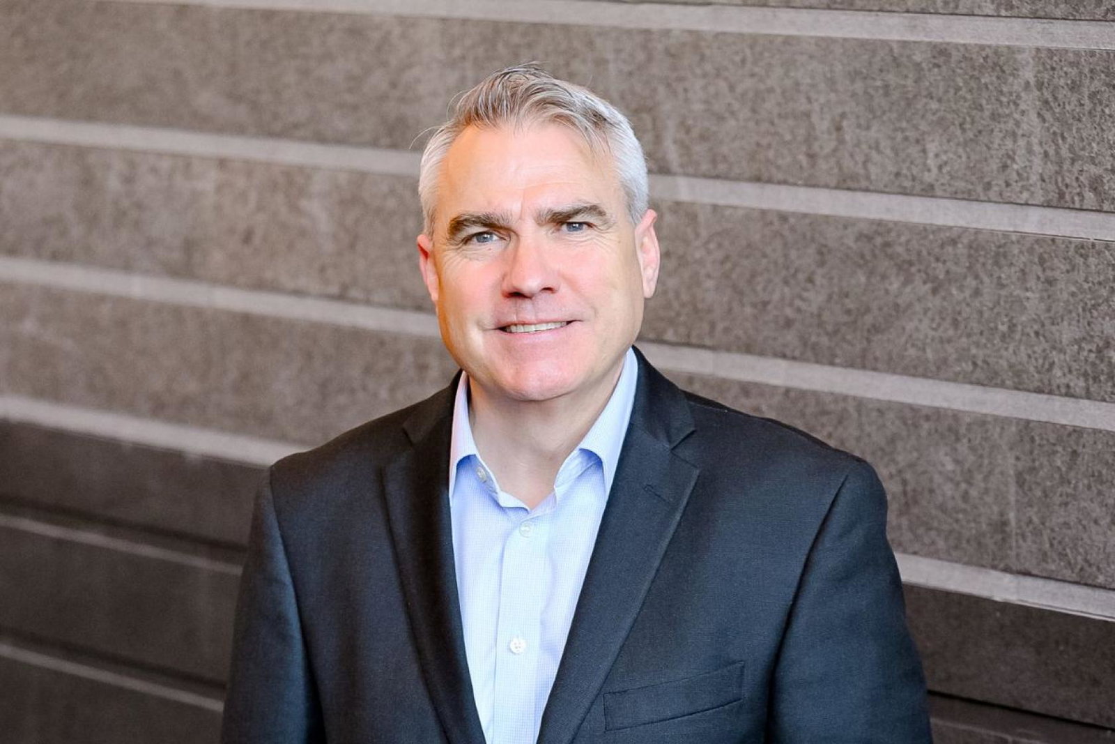Man with grey hair and suit smiling 