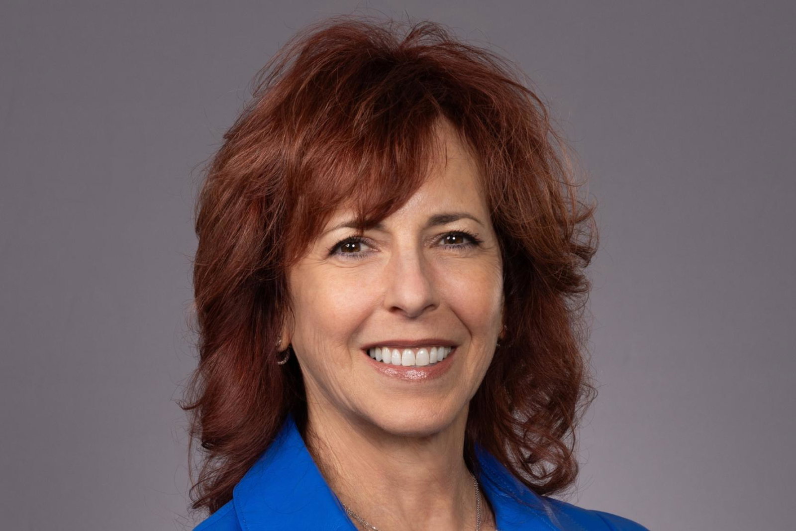 Professional headshot of smiling white woman with red hair
