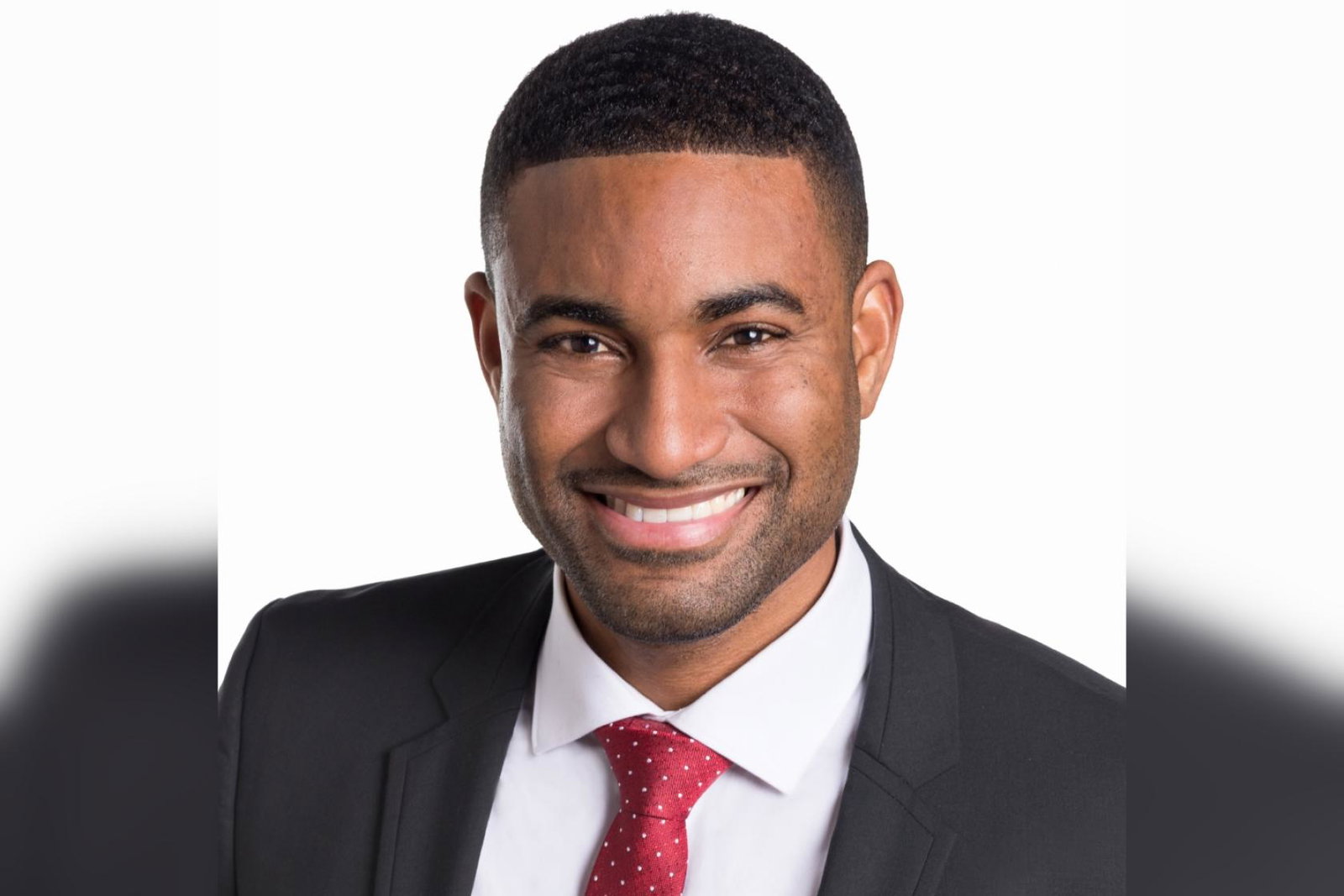 Professional headshot of Black man wearing suit and smiling 