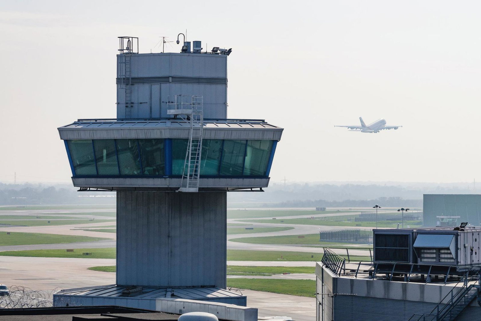 An aircraft takes off behind an airport air traffic control tower