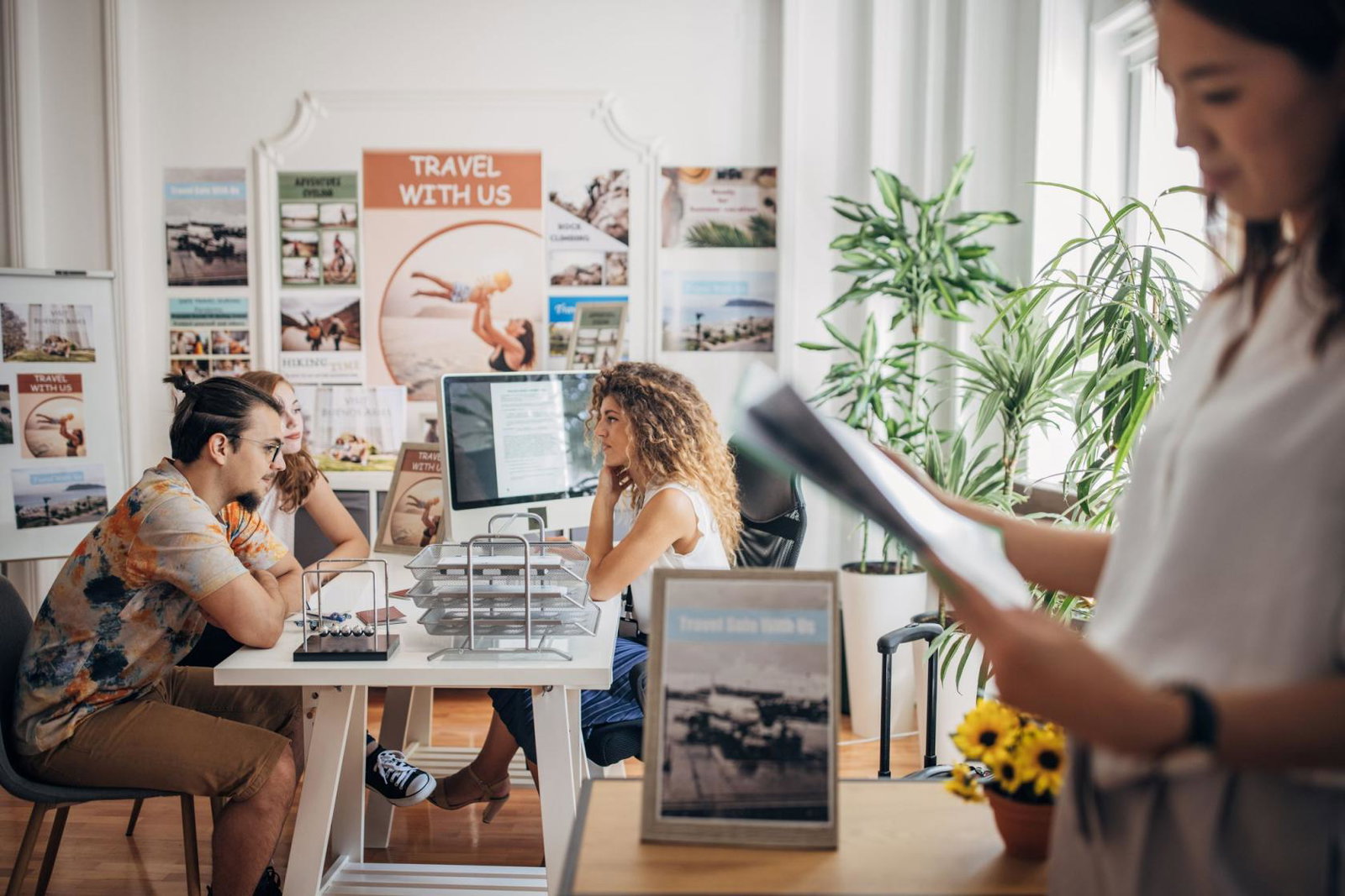 Clients chat to a travel agent in a busy travel agency