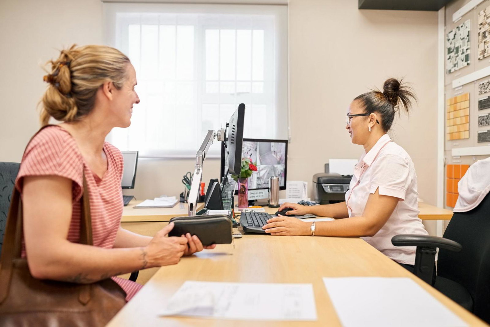 Travel agent working at her desk with a female customer at tiles store office stock photo
