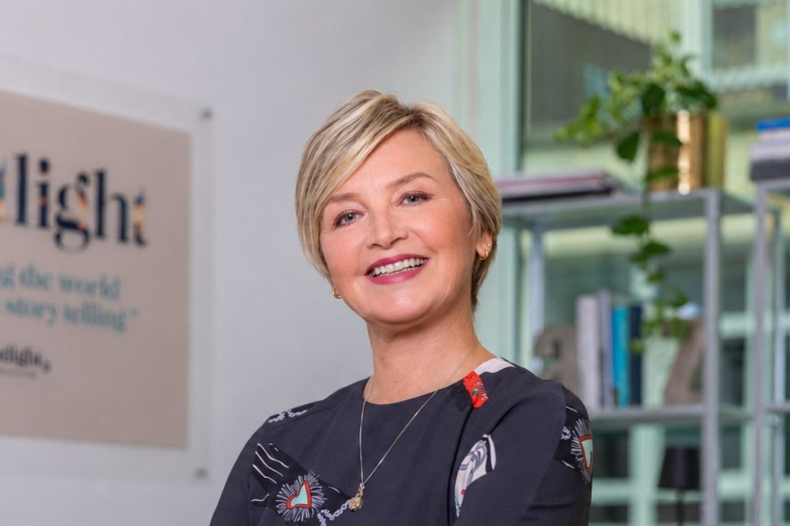 Professional head shot of white woman with short blonde hair. She is smiling. 