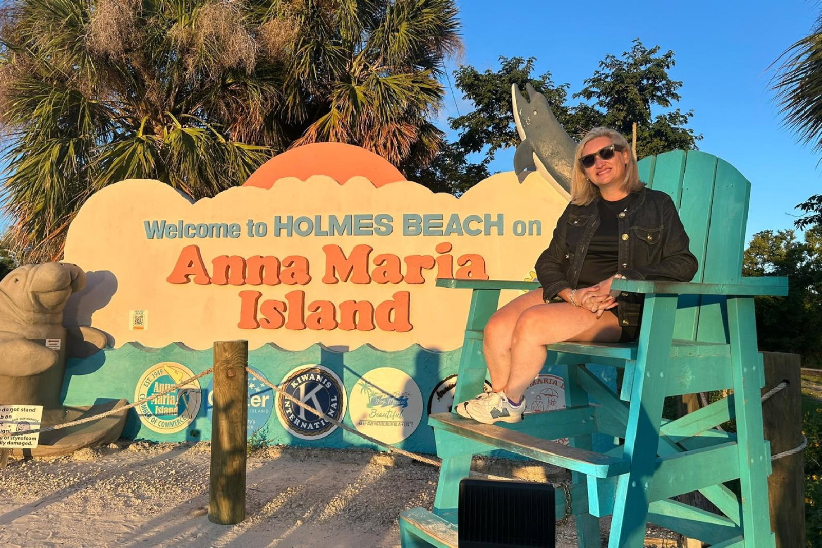 Woman smiling in front of sign 