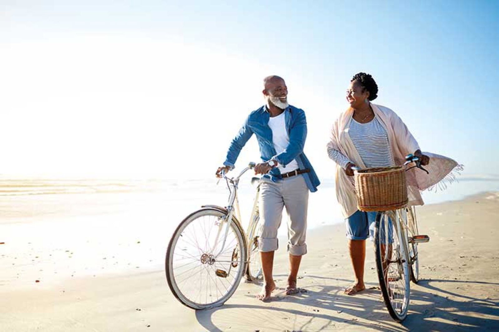 Over-50s couple with bicycles on the beach