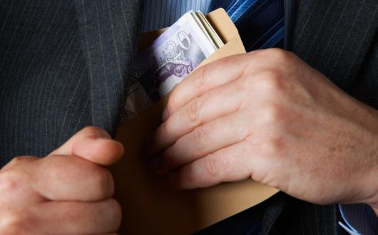 A man places a roll of bank notes in his jacket pocket