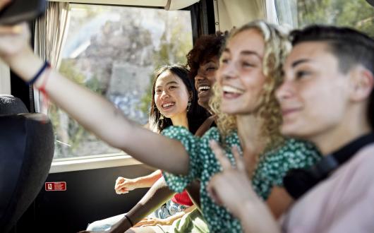 Young people taking a selfie while travelling on a coach
