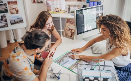 A travel agent helps a young couple with an enquiry