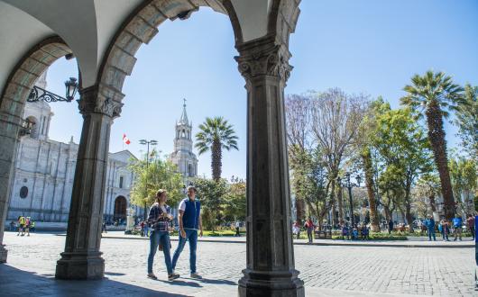 Two people walk through historic central square of Arequipa
