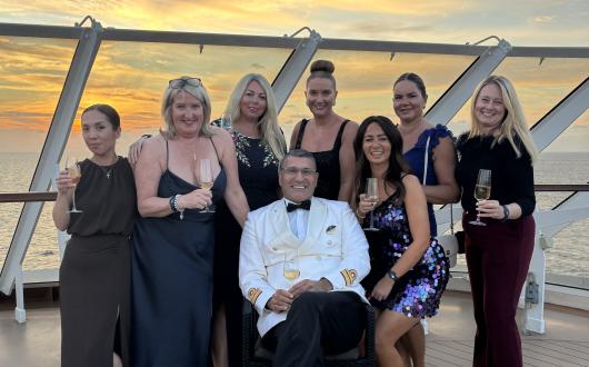 Travel agents stand behind MSC Yacht Club director with sunset in background