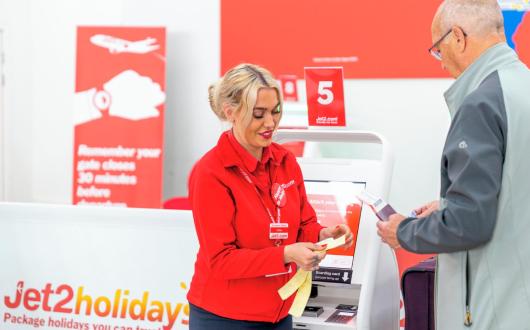 A member of Jet2 check-in staff assisting a passenger