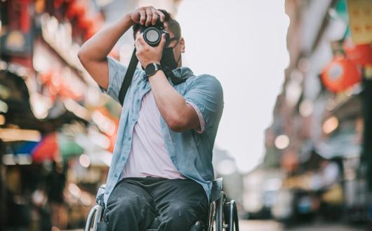 A wheelchair user takes a picture while travelling in an Asian city