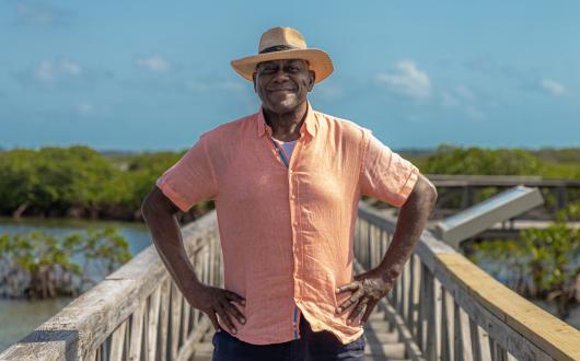 Ainsley Harriot standing with hands on hips on boardwalk over mangrove
