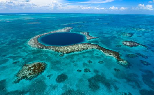 View of Belize Blue Hole from above, a dark blue circle in the middle of clear ocean
