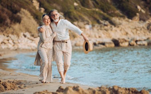 An older couple walk along the beach on holiday
