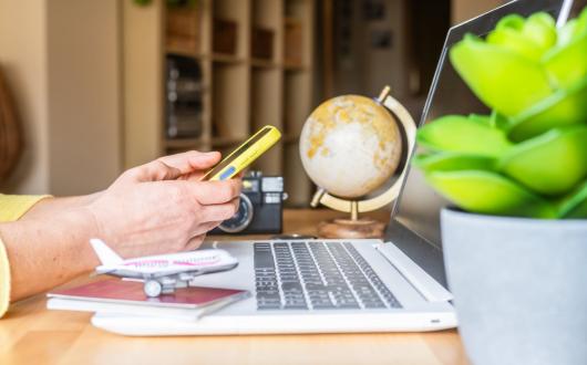Person using a phone sitting at a laptop