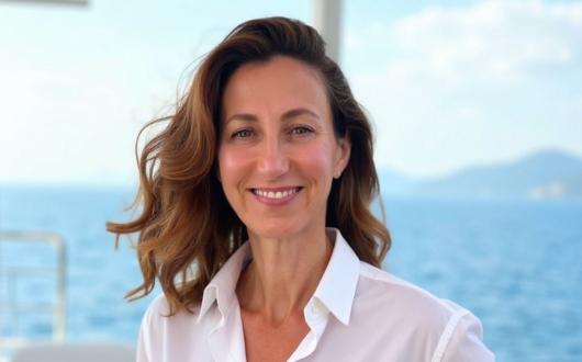 Smiling middle-aged woman with long brown hair and a white shirt 