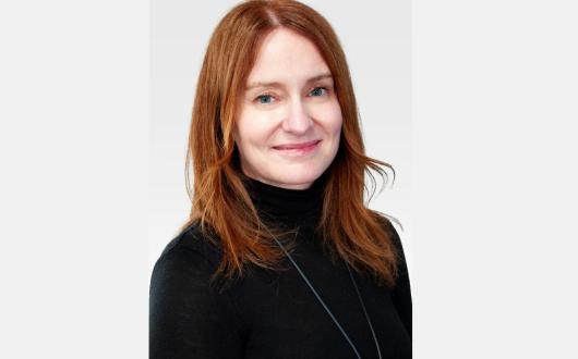 Smiling woman with red long hair and black turtleneck 