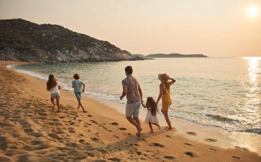 A family of five frolic happily on a sunny beach