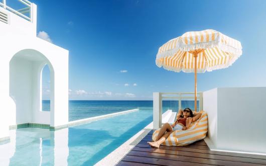 Girl relaxing on sun lounger in beachside resort with infinity pool