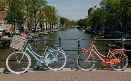 Bikes rest on hand rail with canal view in background in Amsterdam